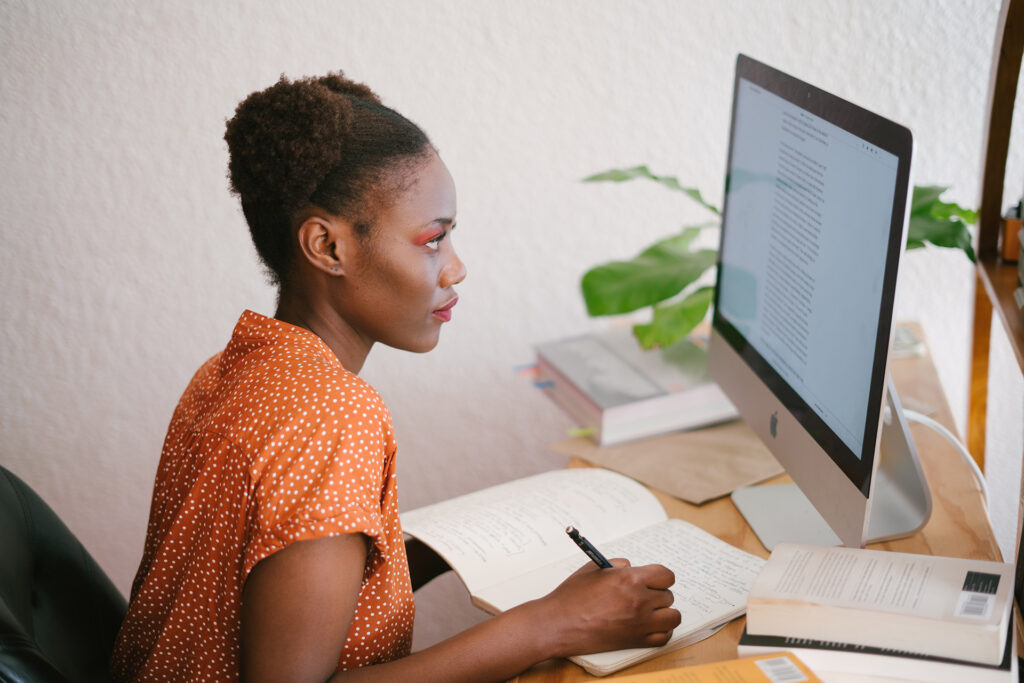 person looking at computer and taking notes